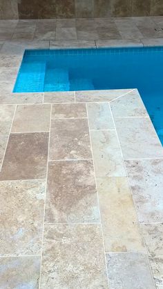 an empty swimming pool surrounded by tiled flooring