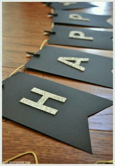 black and gold banner with glitter letters on it sitting on a wooden table in front of a wood floor