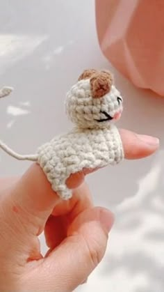 a small crocheted animal is being held by someone's hand with the other hand