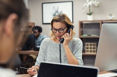 a woman talking on the phone while using a laptop