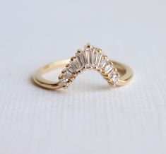 a yellow gold ring with three stones on it's side, sitting on a white surface