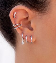 a woman wearing three different types of ear piercings