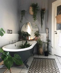 a bath tub sitting next to a mirror and potted plants