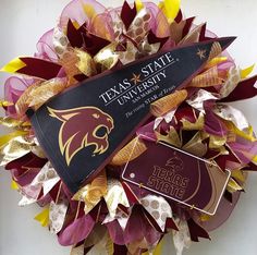 the texas state university wreath is decorated with gold, purple and red paper leaves on it