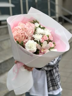 a person holding a bouquet of flowers in their hands on the street with stairs behind them