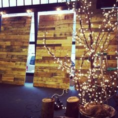 there is a tree that has been decorated with lights and wood planks in the background