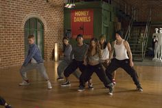 a group of young people standing around each other on top of a hard wood floor