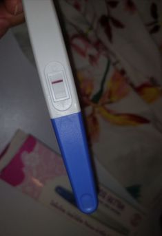 a blue and white toothbrush in someone's hand on a floral print sheet