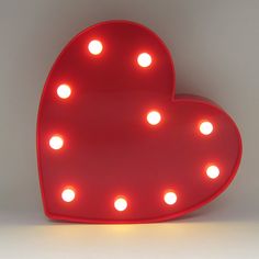 a red heart shaped light up sign sitting on top of a table