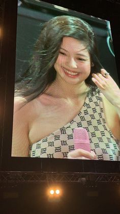 a woman holding a cell phone in front of a large screen