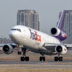 a fedex airplane taking off from an airport runway with the city in the background