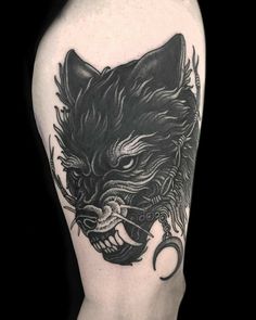 a black and white tattoo on the back of a man's arm with an animal head