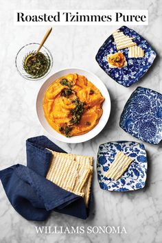 a bowl of pasta with spinach and crackers next to it on a marble table