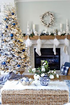 a decorated christmas tree in front of a fireplace with blue and white ornaments on it