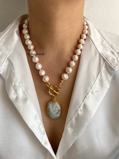 ✨Discover the elegance of our **Gold-Plated Necklace** featuring **Large White Baroque Pearls** and a mesmerizing **Moonstone Pendant**. This handcrafted piece is perfect for adding a touch of luxury and natural beauty to any outfit. ✨ **Exquisite Baroque Pearls The necklace is adorned with large, genuine white baroque pearls, each with its own unique shape and lustrous finish. These pearls bring a timeless elegance to your jewelry collection. 🌙 **Mystical Moonstone Pendant The centerpiece of t Elegant Toggle Necklace With Round Pendant, Elegant Pendant Pearl Necklace With Gemstone Beads, Elegant Toggle Necklace With Natural Stones For Gift, Elegant Pearl Necklace With Natural Stones, Elegant Pearl Pendant Necklace With Gemstone Beads, Elegant Gold Toggle Necklace With Natural Stones, Elegant Toggle Necklace With Gemstone Beads For Gift, Elegant Gold Toggle Necklace With Gemstone, Large Baroque Pearl Necklace