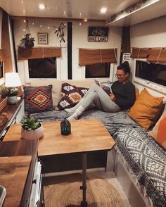 a woman sitting on top of a couch in a living room next to a table