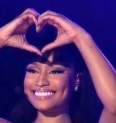 a woman making a heart shape with her hands on top of her head while smiling at the camera