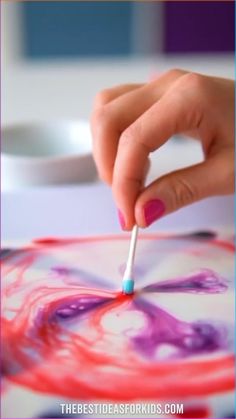 a person is painting on a piece of paper with a toothbrush in their hand