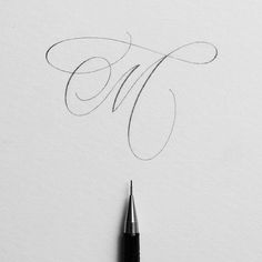 a pen is writing the letter k in cursive ink on white paper with a black marker