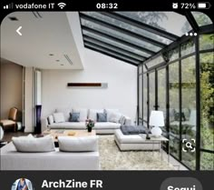 a living room filled with lots of white furniture and large glass windows on the ceiling