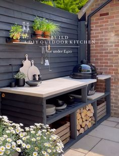 an outdoor kitchen with potted plants on the outside wall and shelves for cooking utensils