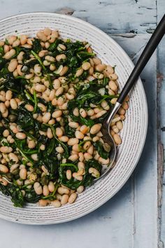 a white bowl filled with beans and spinach