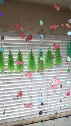 a window with some green decorations hanging from it's side and on top of the blinds