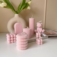 pink candles and decorations on a table next to a vase with tulips in it