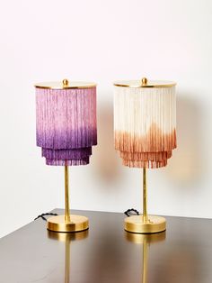 two lamps with shades of pink and purple sitting on top of a table next to each other