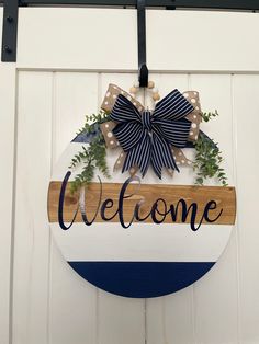 a welcome sign hanging from the side of a white door with blue and white stripes