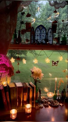 candles, books and flowers on a table in front of a window