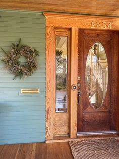 a wooden door with a wreath on the side of it next to a blue house