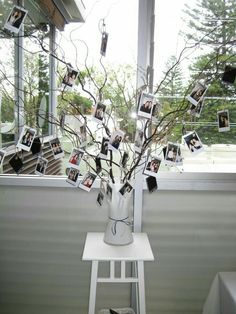 a vase filled with pictures sitting on top of a white table next to a window