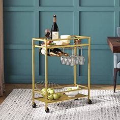 a bar cart with wine glasses and bottles on it in front of a blue wall