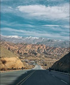 an empty road with mountains in the background