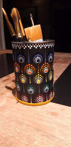 a wooden table topped with a black container filled with brushes and other items on top of it