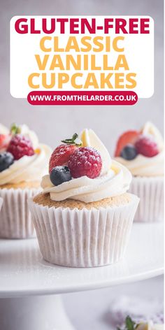 three cupcakes with white frosting and fruit on top, sitting on a cake plate