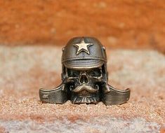 a small metal skull wearing a helmet with a star on it's head sitting in the sand