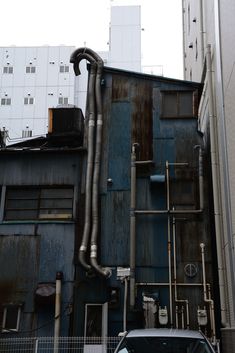 a car parked in front of a building with pipes coming out of it's side