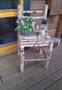 a chair made out of branches with flowers on it and a lantern in the back