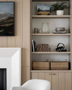 a white chair sitting in front of a fireplace next to a book shelf filled with books