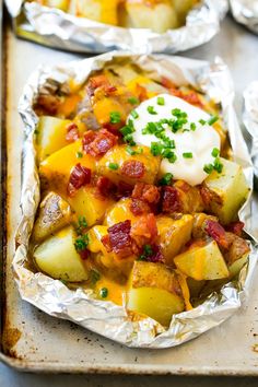 baked potato casserole with bacon and sour cream in tin foil on a baking sheet