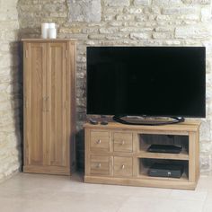 a flat screen tv sitting on top of a wooden cabinet next to a brick wall