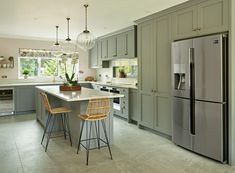 a kitchen with two stools next to an island in front of a refrigerator and sink