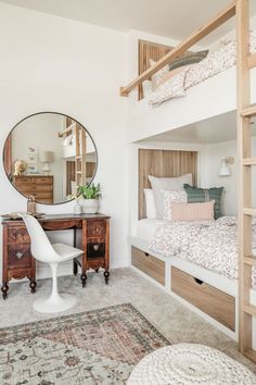 a bedroom with bunk beds and a desk in the corner next to a mirror on the wall