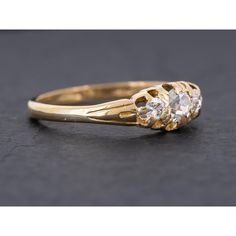 a gold ring with two diamonds on it, sitting on a black surface and facing the camera