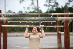 a woman is doing pull ups on a bar in the parking lot while holding her hands behind her head