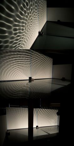 the light is shining on the wall and reflecting off it's glass surface, creating an interesting pattern