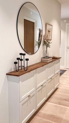 a large mirror hanging on the side of a white wall next to a wooden floor