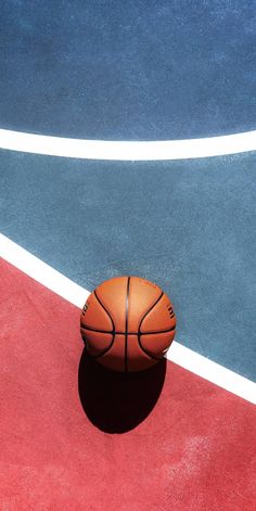 a basketball sitting on top of a court next to a red and blue floor with white lines